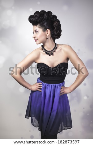 Attractive young woman with professional make-up and hair style. Posing in short beautiful dress. With handmade jewelry.