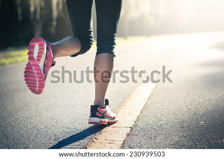 Sporty woman running on road at sunrise. Fitness and workout wellness concept.