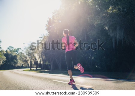 Sportive woman running outside at sunrise on the road. Fitness and wellness concept.