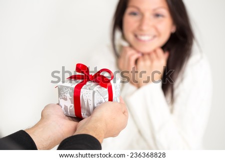Man giving a Christmas gift to a beautiful young woman . Girl receiving a present.