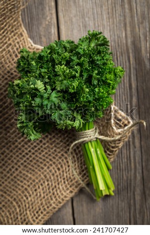Fresh garden parsley on burlap sack. On wooden table.