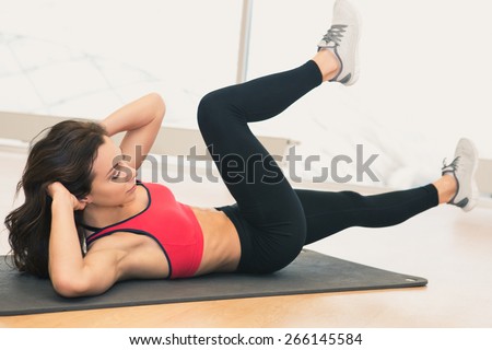 Young woman doing abs workout in a gym on a mat. Sport and lifestyle concept.