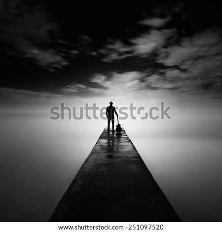 Silhouette man standing with guitar at jetty or pier in black and white