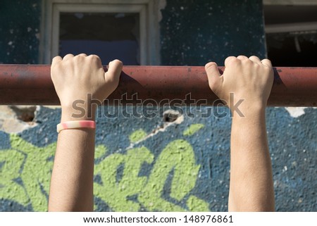 girl playing on metal bars hanging from her hands