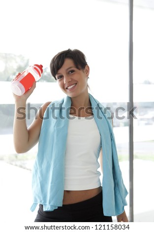 girl with sport water bottle in hand and towel after workout
