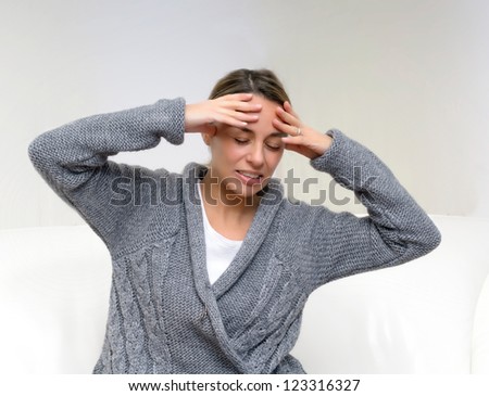 Closeup of pretty young woman suffering from head pain while sitting at home