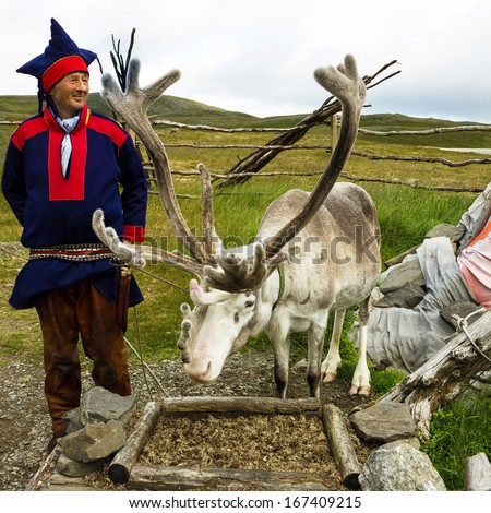 Deer And Reindeer Breeder Dressed In National Clothes The Sami In Honningsvag, Norway. The Sami Are The People Inhabiting The Arctic