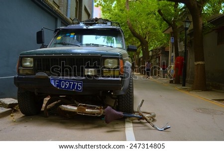BEIJING, CHINA, AUGUST 20, 2013: bicycle run over by a jeep inside of the hutong area of beijing