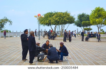 XINJIE, CHINA, NOVEMBER 18, 2013:group of old men is playing games on the main square of xinjie village in yunnan, china.
