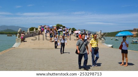 BEIJING, CHINA, AUGUST 15, 2013: People are crossing 17-arch bridge situated on kunming lake in the new summer palace complex in beijing.