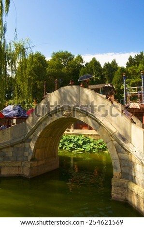 BEIJING, CHINA, AUGUST 15, 2013: People are crossing bridge decorated by several pagodas inside of the new summer palace complex in chinese capital beijing.
