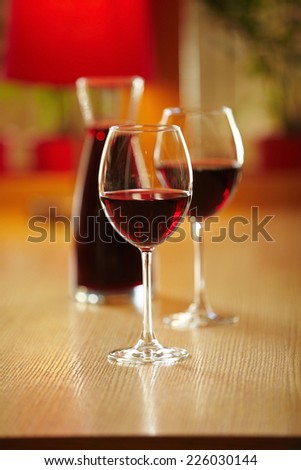 Glasses of wine with jar on the background