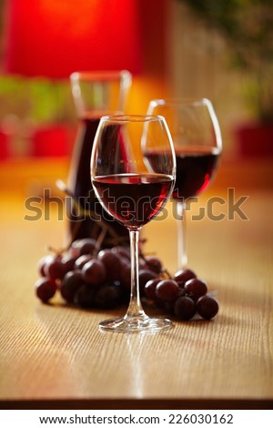 Glasses of wine with jar and grapes on the background