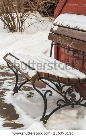 Snow-covered bench in the garden on a frosty winter day