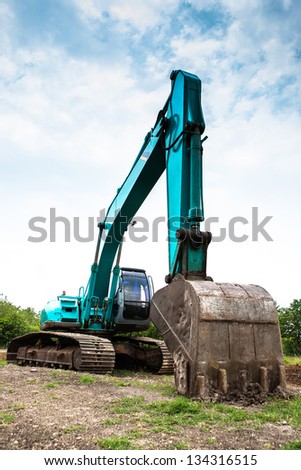 Heavy machine, bulldozer on the field with cloudy blue sky