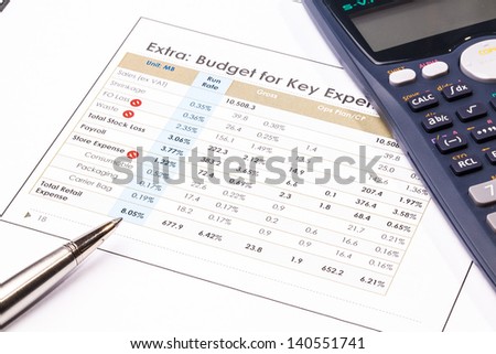 Finance report sheet with calculator and metal pen