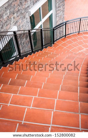 Curve stairs decorated with orange stone pile with black iron handrail