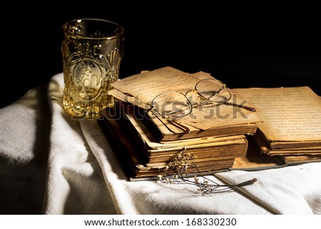 Aged book on white cloth with vintage glass