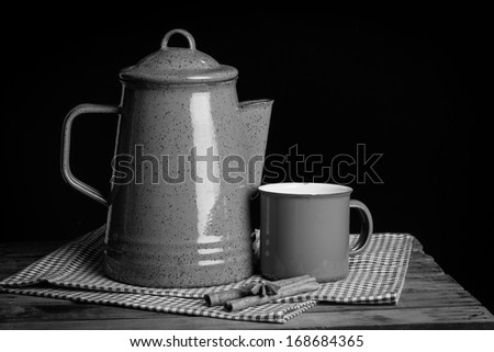 Still life, red tea pot set and cinnamon sticks on table cloths in dark background