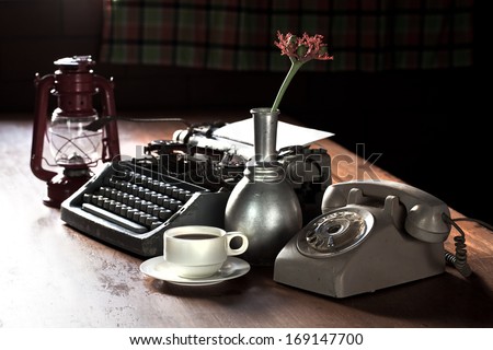 Still life of retro office, telephone, type writer and flower in silver vase place near old lamp on wooden table