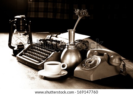 Still life of retro office, telephone, type writer and flower in silver vase place near old lamp on wooden table