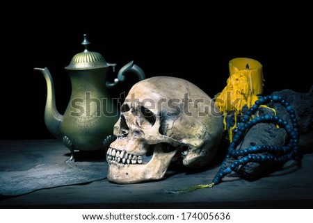 Still life with skull on old book,  dry rose, count unit and brass tea pot