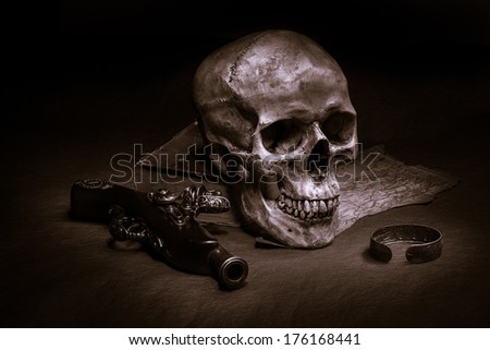 Still life, skull with ancient gun, silver bracelet and old book on map