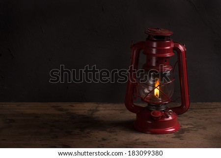 Old fashioned vintage kerosene oil lantern lamp burning with a soft glow light with aged wooden floor
