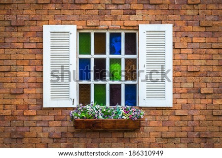 detail of a wooden window with shutters open and flowers box on brick wall
