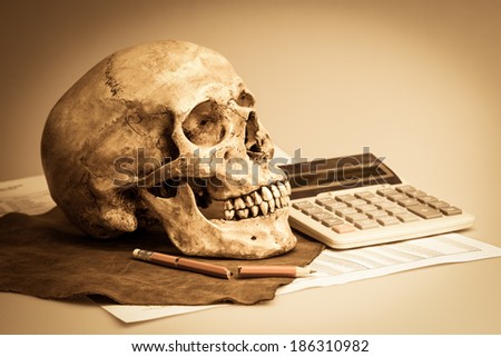 still life with human skull on leather, broken pencil, calculator and finance report