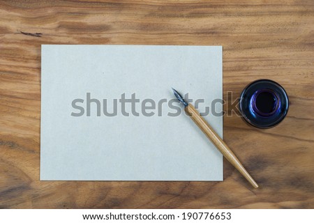 old fashioned ink dip pen for writing or drawing on wooden table with parchment paper background