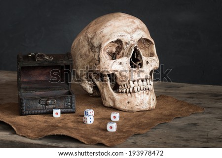 Still life with human skull, dices and leather box