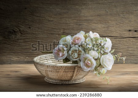 Still life with  bunch of roses and empty basket on wooden table
