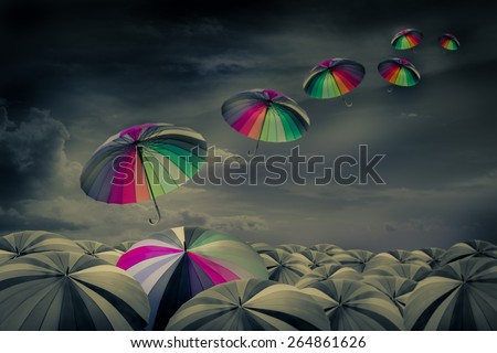 rainbow umbrella in the mass of black umbrellas