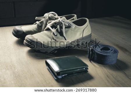 Sneakers, wallet,and belt on table top. still life