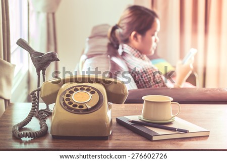 Technology change concept, young woman use smartphone near old telephone on wooden table