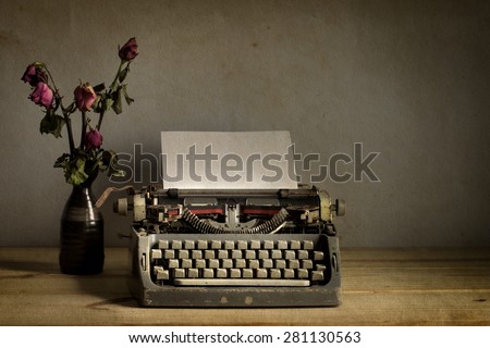 Still life with old typewriter with dry rose flowers on wooden  table