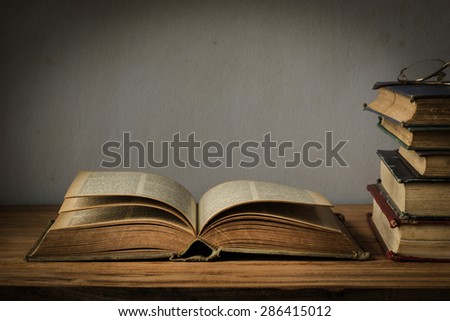 old book open on a wooden table with glasses