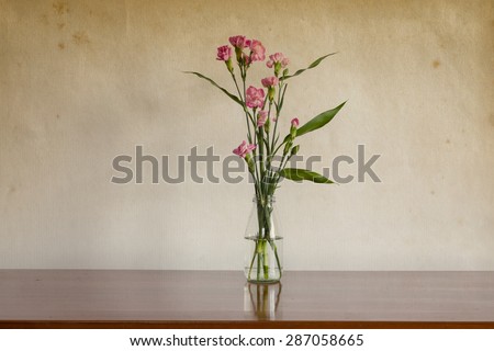 Still life with flowers in glass bottle on wooden table