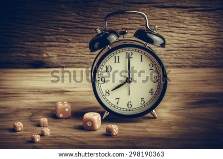 Still life with alarm clock and red dices on the wooden table