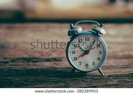 Vintage alarm clock on weathered wood background