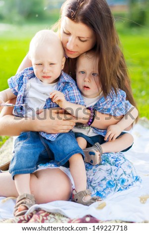Young Mother can\'t calm her twins, in a park