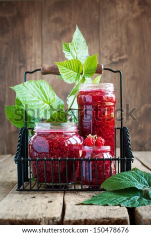 Raspberry Jam in a jars and Leaves on the wooden background