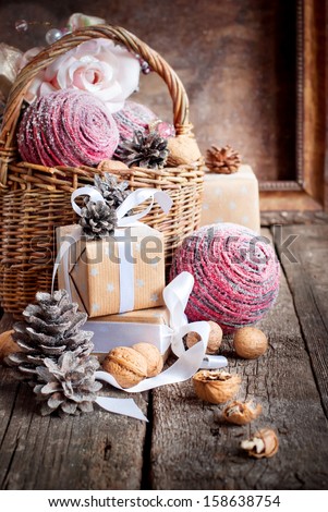 Vintage Christmas Card With Basket, Gifts, Boxes, Walnuts, Balls And Pine Cones On Wooden Background