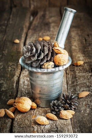Natural Christmas Gifts in a mortar with walnuts, pine cones and almonds on wooden background
