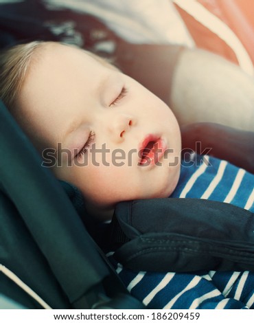 Portrait of Little Boy Sleeping in Car Seat, image with toning and effect of soft shining sun