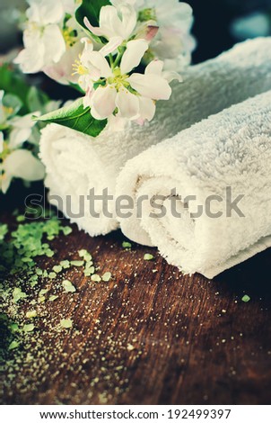 Spa and Wellness Setting with salt, white towels, flowers on wooden background