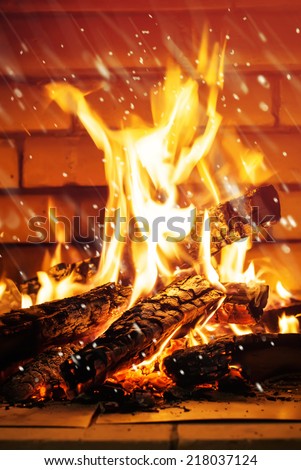 Flame of Fire in a Fireplace with effect falling Snow, on a brickwall background
