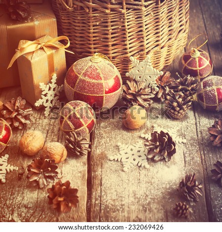 Vintage Toned Image with Christmas Gifts in Magic Lights with Basket, Red balls, Pine cones, Pine cones, Boxes, Walnuts and Snowflakes. Country style