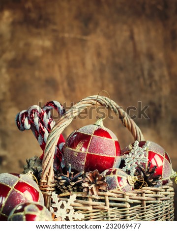 Christmas Composition with Vintage Country Gifts on Warn Wooden Background. Basket, red balls, pine cones, sweets. Copy space